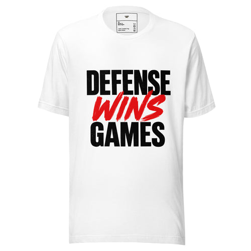 A white short-sleeve crewneck t-shirt featuring the slogan 'DEFENSE WINS GAMES' printed on the chest. 'DEFENSE' and 'GAMES' are in bold black block letters, while 'WINS' is written in a red brush-stroke style font.
